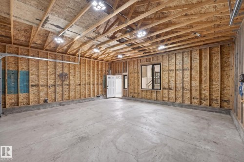 Spacious unfinished garage featuring concrete flooring, exposed wood framing, and multiple overhead light fixtures - 17733 64A Street, Edmonton, AB 