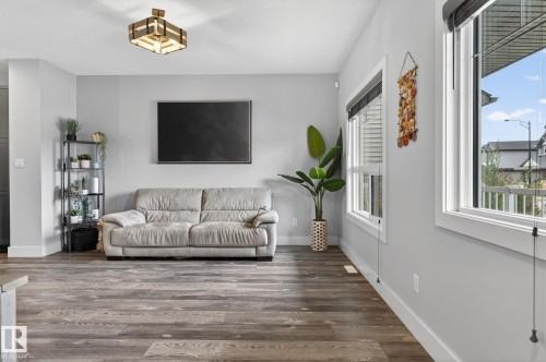 Spacious living area featuring wood-finish flooring, light gray wall tones, and multiple large windows - 17733 64A Street, Edmonton, AB 