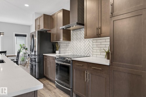 Kitchen featuring wood-finish cabinetry, white countertops, and stainless steel appliances - 17733 64A Street, Edmonton, AB 
