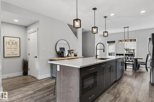 Modern kitchen island featuring a light-toned countertop, integrated microwave, and dark-finish cabinetry - 17733 64A Street, Edmonton, AB 