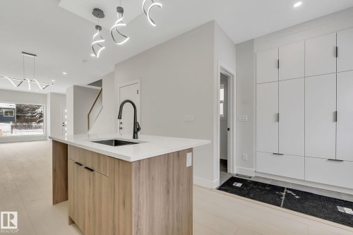 Kitchen island featuring a wood-finish base, integrated black sink, and a matte black faucet - 11132 72 Avenue, Edmonton, AB - Indoor Photo Showing Kitchen