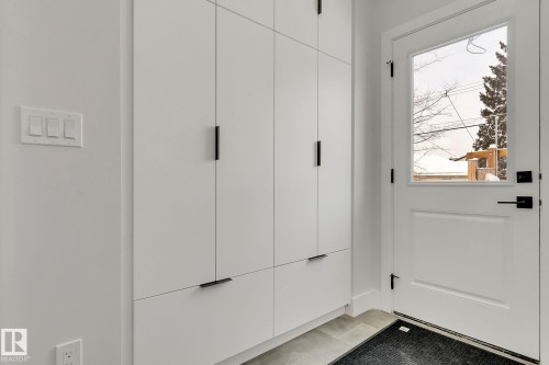 Full-height white cabinetry with matte black hardware, a white door with a clear glass insert, and light gray floor tiles - 11132 72 Avenue, Edmonton, AB - Indoor Photo Showing Other Room