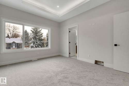 Room featuring a large window, light gray carpet, and tray ceiling with recessed lighting - 11132 72 Avenue, Edmonton, AB - Indoor Photo Showing Other Room