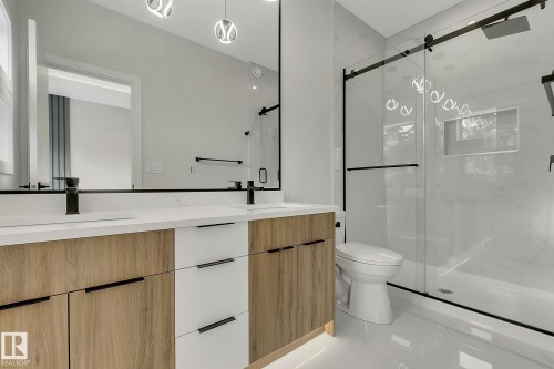 Contemporary bathroom featuring a double vanity with wood-finish and white cabinetry, a large mirrored wall, and dual matte black faucets - 11132 72 Avenue, Edmonton, AB - Indoor Photo Showing Bathroom