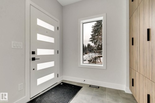 Entryway featuring a contemporary white door with frosted glass inserts, a single pane vertical window, and wood-look cabinetry with black hardware - 11132 72 Avenue, Edmonton, AB - Indoor Photo Showing Other Room