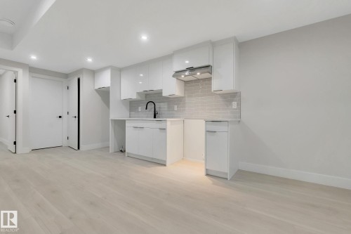 Contemporary kitchen area featuring white shaker-style cabinetry, a gray subway tile backsplash, and a matte black gooseneck faucet - 11132 72 Avenue, Edmonton, AB - Indoor