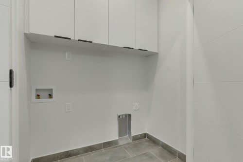 Laundry area featuring white cabinetry with dark pulls, a tiled floor, and appliance hookups - 11132 72 Avenue, Edmonton, AB - Indoor