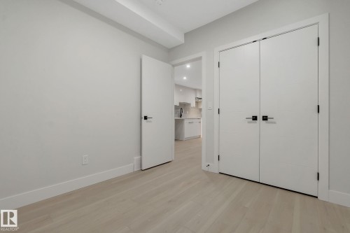 Neutral-toned walls and wood-finish flooring characterize this room, featuring a white bi-fold closet door with black hardware - 11132 72 Avenue, Edmonton, AB - Indoor Photo Showing Other Room