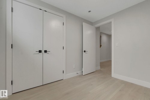 Light wood-finish flooring complements the neutral wall color - 11132 72 Avenue, Edmonton, AB - Indoor Photo Showing Other Room