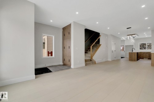 Bright open-concept living area featuring light wood-finish flooring, recessed lighting, and a modern chandelier - 11132 72 Avenue, Edmonton, AB - Indoor Photo Showing Other Room