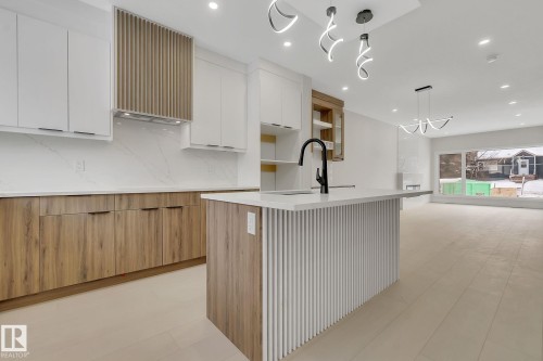 Contemporary kitchen featuring a large central island with vertical slat detailing and a black gooseneck faucet - 11132 72 Avenue, Edmonton, AB - Indoor Photo Showing Kitchen