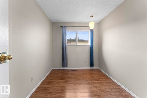Bright room featuring wood-finish flooring, a double window, and a ceiling-mounted light fixture - 210 22 Street, Cold Lake, AB 