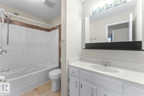 Bathroom featuring a white vanity with integrated sink, chrome faucet, and a wall-mounted mirror with overhead lighting - 210 22 Street, Cold Lake, AB 