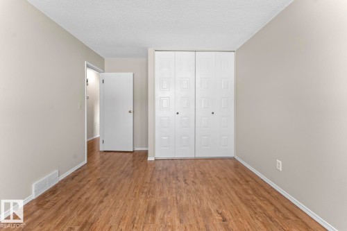 Warm neutral wall tones, wood-finish flooring, white baseboards, and a textured white ceiling - 210 22 Street, Cold Lake, AB 