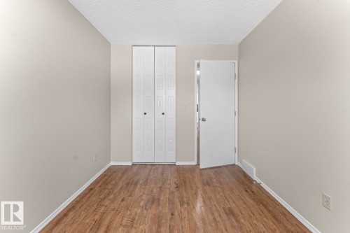 Room featuring wood-finish flooring, light neutral wall paint, and white baseboards - 210 22 Street, Cold Lake, AB 