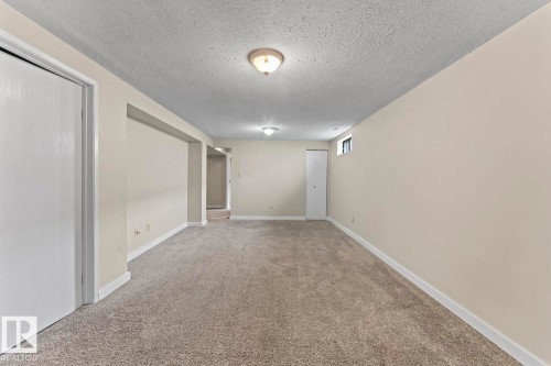 Spacious room featuring neutral carpeting, light-toned wall paint, and white trim - 210 22 Street, Cold Lake, AB 