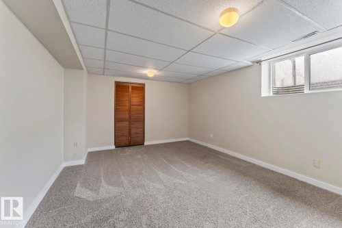 Spacious room featuring neutral carpeting, light-toned walls, and a drop ceiling with integrated lighting - 210 22 Street, Cold Lake, AB 