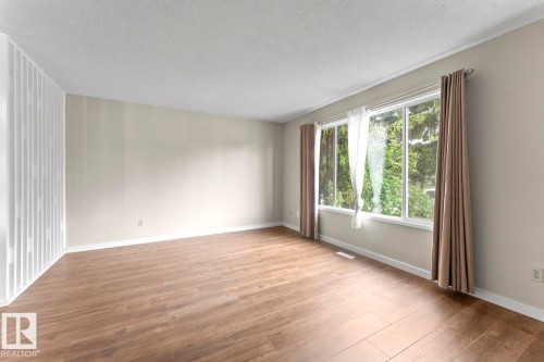 Bright interior space featuring wood-finish flooring, light-toned wall paint, and white baseboards - 210 22 Street, Cold Lake, AB 