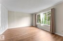 Bright interior space featuring wood-finish flooring, light-toned wall paint, and white baseboards - 210 22 Street, Cold Lake, AB 