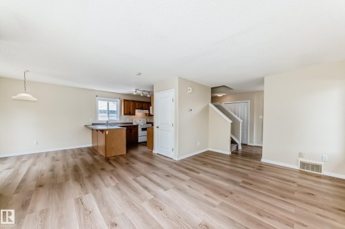 Spacious living area featuring wood-finish flooring, neutral wall tones, and recessed lighting - 3711 22A St, Edmonton, AB 