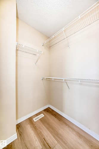 Walk-in closet featuring wood-finish flooring, white wire shelving, and neutral wall tones - 3711 22A St, Edmonton, AB 