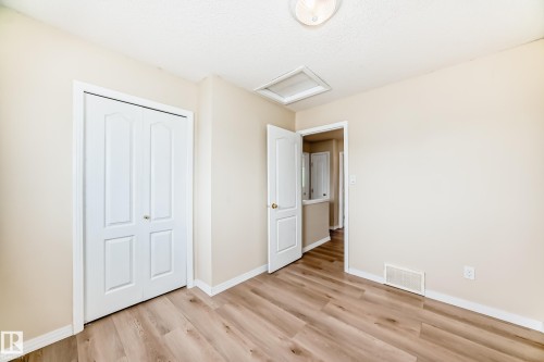 Room with wood-finish flooring, light-toned walls, white baseboards, and a bi-fold closet door - 3711 22A St, Edmonton, AB 