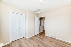 Room with wood-finish flooring, light-toned walls, white baseboards, and a bi-fold closet door - 