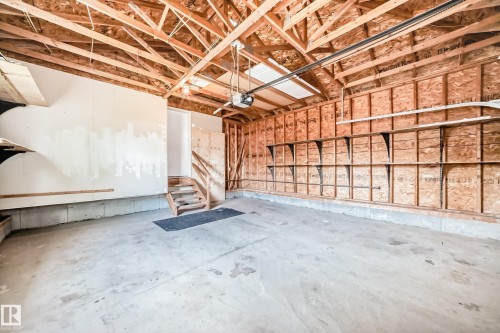 Spacious garage with exposed wood ceiling trusses, concrete flooring, and built-in shelving - 3711 22A St, Edmonton, AB 