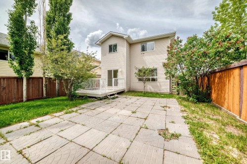 Rear exterior featuring a spacious concrete patio, a private wood deck with white railing, and a sliding glass door entry - 3711 22A St, Edmonton, AB 
