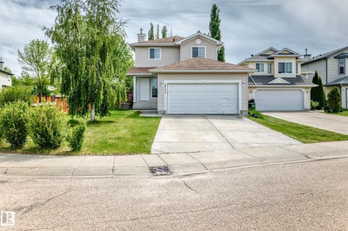 Two-story residence featuring light-colored siding, a brown shingle roof, and a two-car attached garage - 3711 22A St, Edmonton, AB 