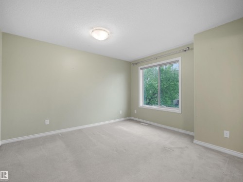 Spacious room featuring light green walls, a large window, white trim, and light grey carpeting - 21316 45A Avenue Nw, Edmonton, AB 