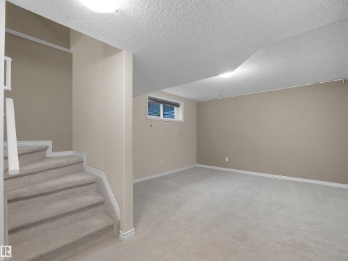 Carpeted staircase with white railing leading to a versatile lower-level space - 21316 45A Avenue Nw, Edmonton, AB 