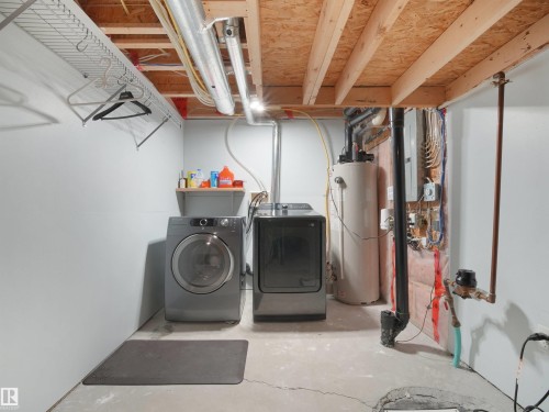 Utility area featuring concrete flooring, exposed ceiling joists, and a hot water heater - 21316 45A Avenue Nw, Edmonton, AB 