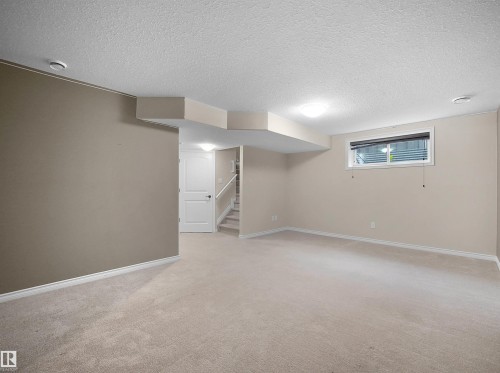 Carpeted lower level with neutral-toned walls, white trim, and a white paneled door - 21316 45A Avenue Nw, Edmonton, AB 