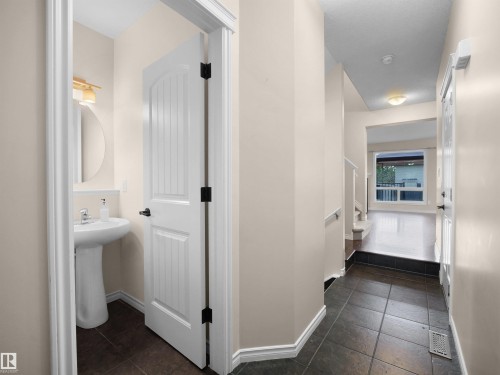 Entryway featuring dark tile flooring, leading to a space with wood-finish flooring and a large window - 21316 45A Avenue Nw, Edmonton, AB 