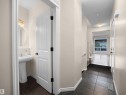 Entryway featuring dark tile flooring, leading to a space with wood-finish flooring and a large window - 21316 45A Avenue Nw, Edmonton, AB 