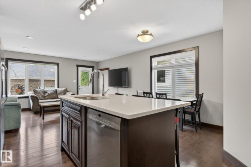 Central kitchen island with a single-basin sink, gooseneck faucet, and integrated stainless steel dishwasher - 8506 80 Avenue, Edmonton, AB 