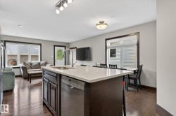 Central kitchen island with a single-basin sink, gooseneck faucet, and integrated stainless steel dishwasher - 