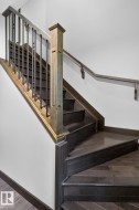 Hardwood staircase featuring dark wood-finish treads and risers, a light wood-finish newel post, black metal balusters, and a matching wood-finish handrail - 