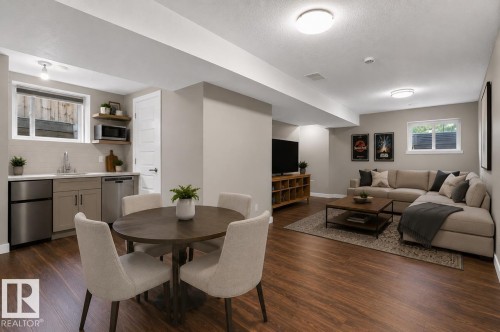 Open-concept living space with wood-finish flooring, recessed lighting, and a neutral wall palette - 8506 80 Avenue, Edmonton, AB 