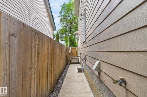 Side yard featuring concrete pathway, wood fence, and light-toned horizontal siding - 8506 80 Avenue, Edmonton, AB 