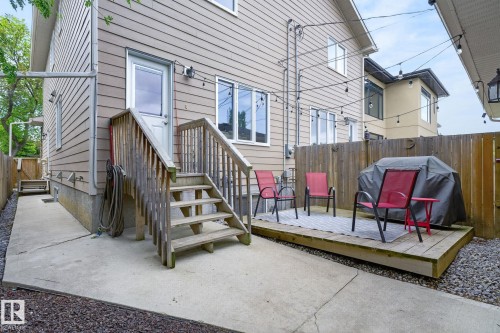 Rear exterior featuring a wood deck, concrete patio, wood fence, and string lighting - 8506 80 Avenue, Edmonton, AB 
