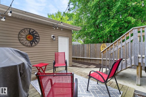 Outdoor wood-finish deck featuring a wood privacy fence, integrated wood stairs, exterior siding, and a stone paver path - 8506 80 Avenue, Edmonton, AB 