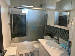 Bathroom with a white bathtub and shower featuring a sliding glass enclosure - 