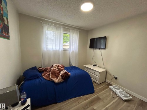 Bedroom featuring wood-finish flooring and a ceiling-mounted light fixture - 10924 30 Street, Edmonton, AB 