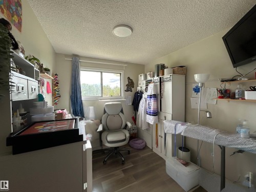 Room featuring wood-finish flooring, a window with natural light, and a ceiling-mounted light fixture - 10924 30 Street, Edmonton, AB 