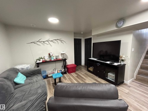 Open concept living area featuring wood-finish flooring, recessed lighting, a built-in entertainment unit, and a staircase with wood-finish treads - 10924 30 Street, Edmonton, AB 