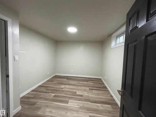 Open room featuring wood-finish flooring, light neutral walls, recessed ceiling lighting, and white baseboards - 10924 30 Street, Edmonton, AB 