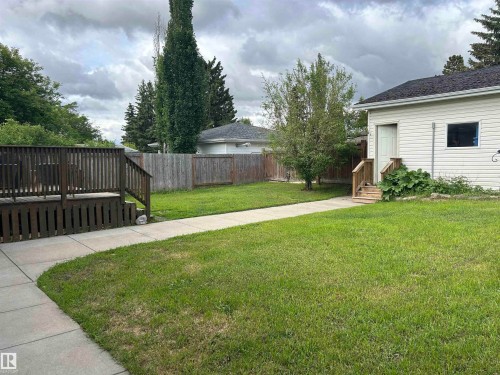 Spacious backyard featuring a wooden deck, a concrete walkway, and a privacy fence - 10924 30 Street, Edmonton, AB 