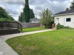 Spacious backyard featuring a wooden deck, a concrete walkway, and a privacy fence - 